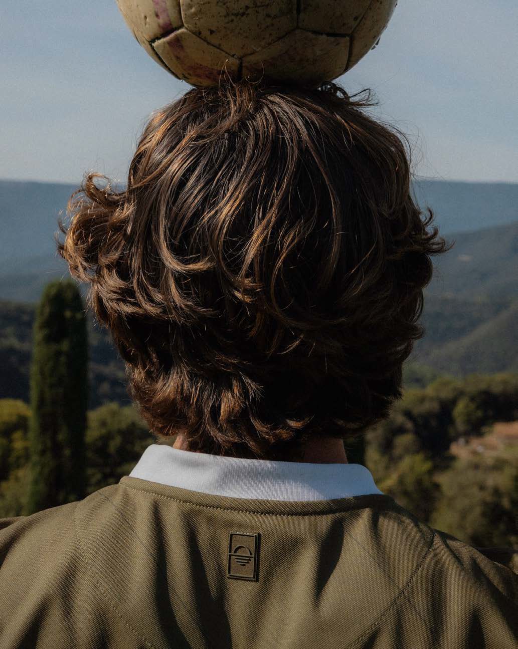 Ball balanced on a head, hills beyond
