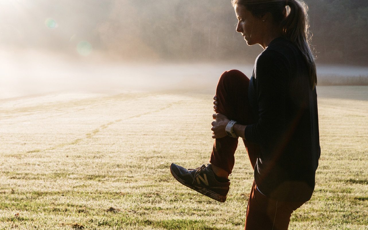 Runner stretching on a misty field